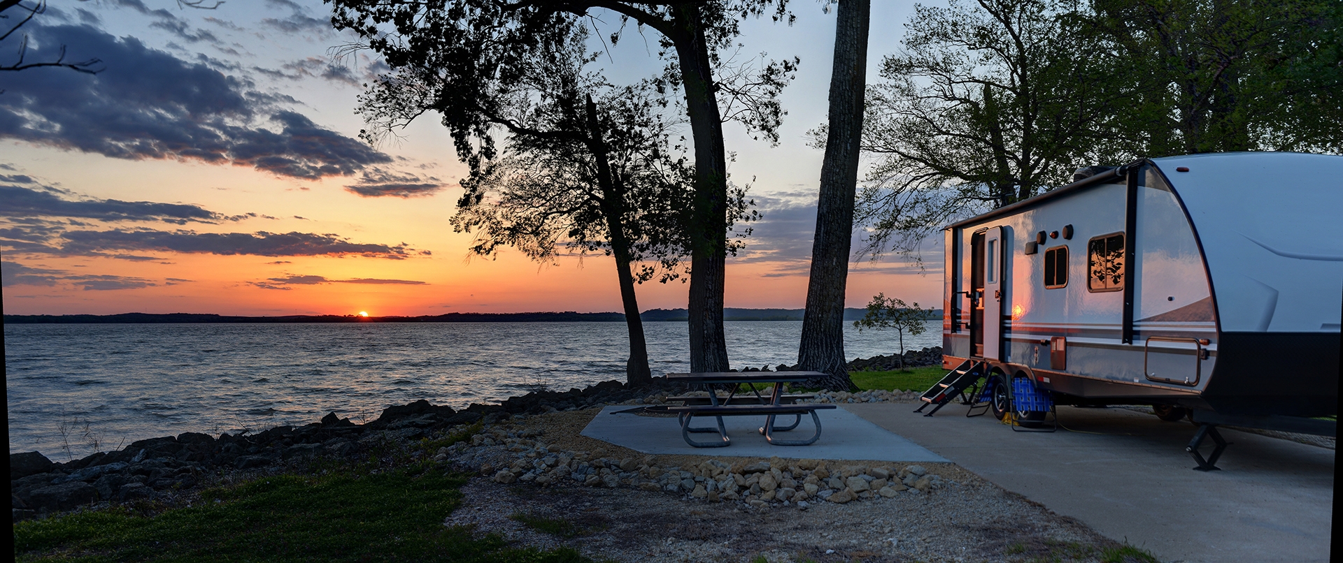 camper at lake during sunset
